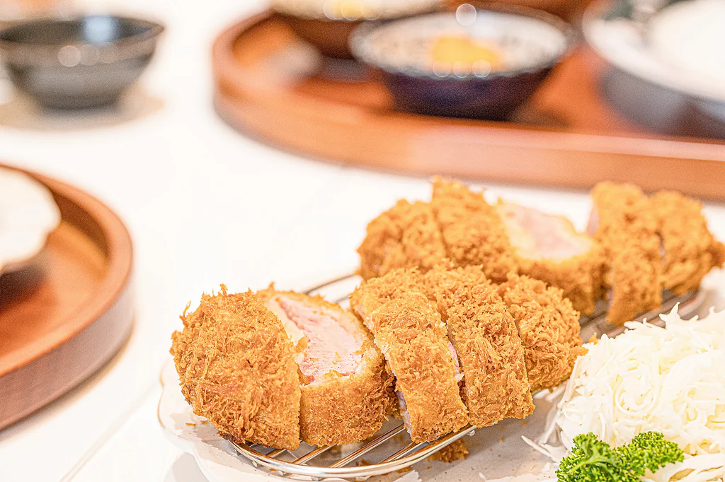 Sepiring hidangan Donkachun dengan tonkatsu berpotongan tebal dan sayuran kol